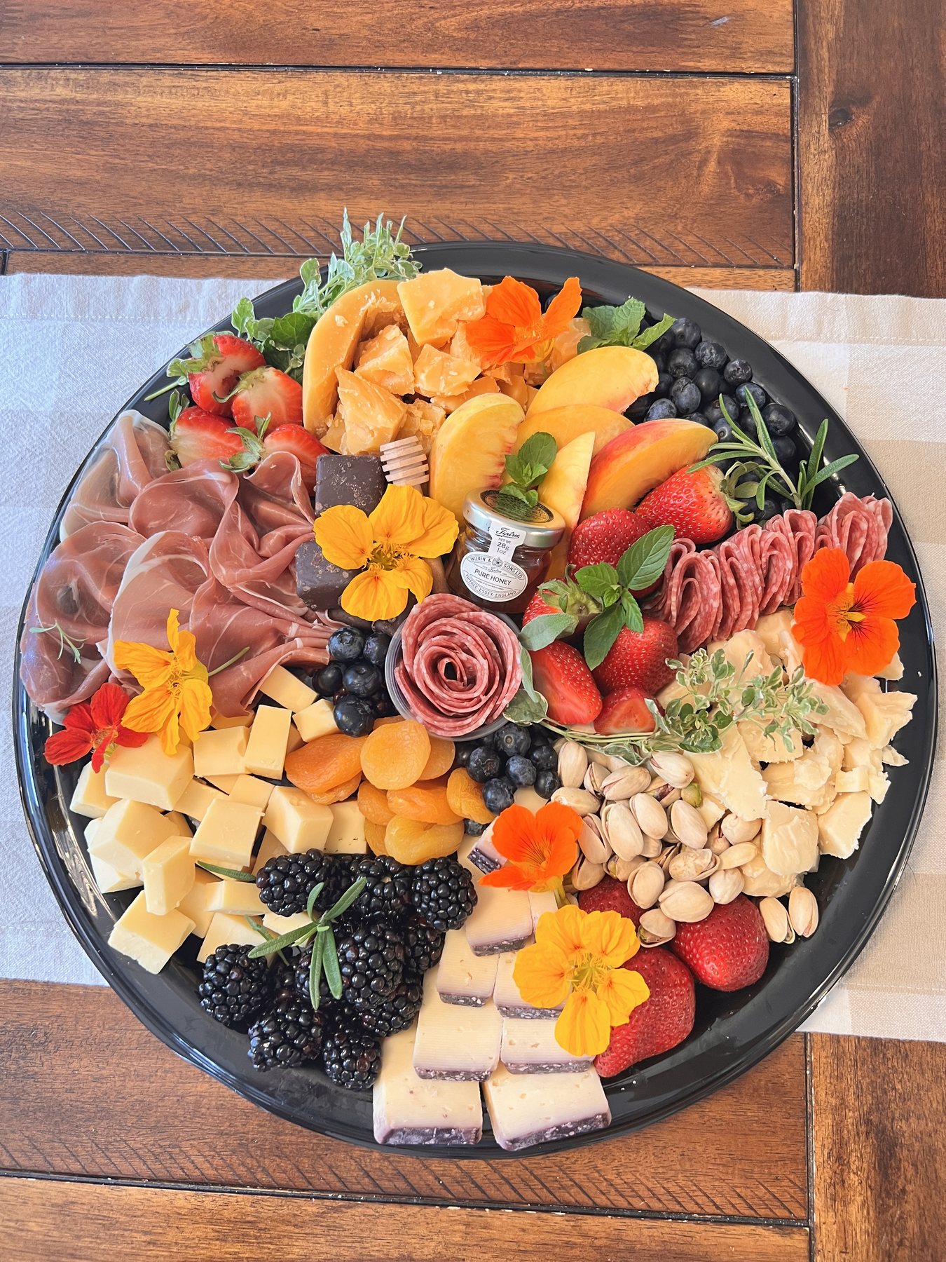 Grazing charcuterie board arranged with cheeses, meats, fruit, nuts, and jams